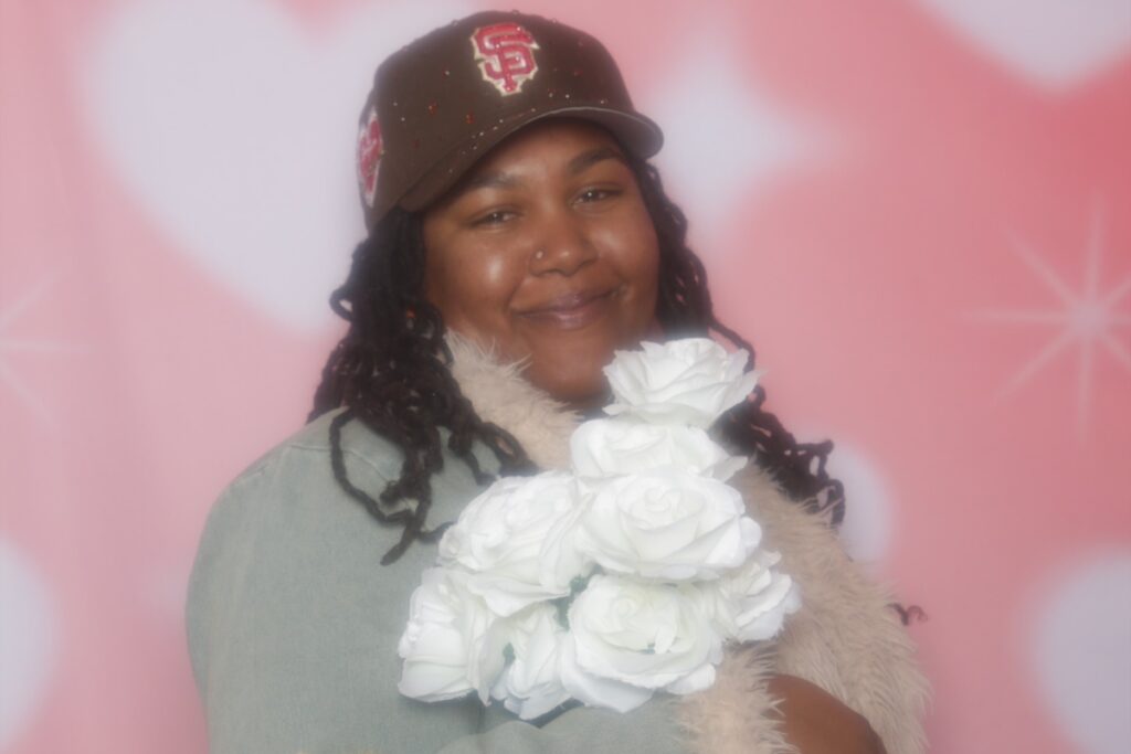 Woman holding white roses against a soft pink backdrop. 