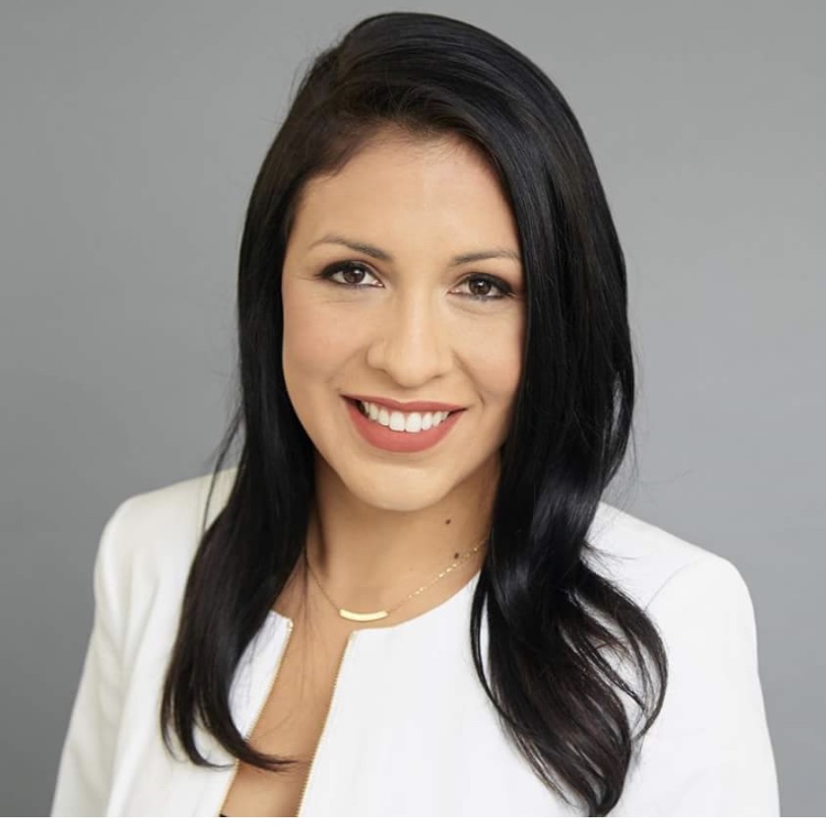 Woman in a white suit, smiling.